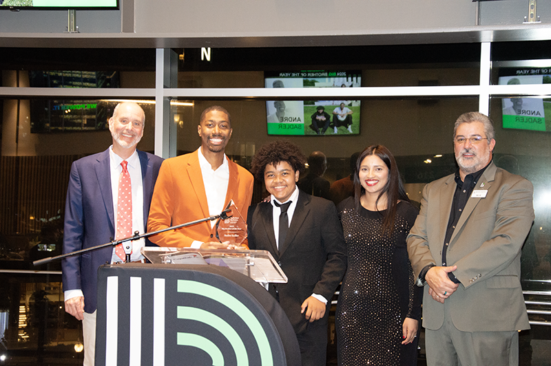 a group photo of young professionals and a teenager posing for an award photo