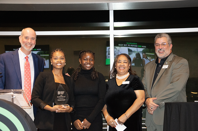 a group photo of young professionals and a teenager posing for an award photo