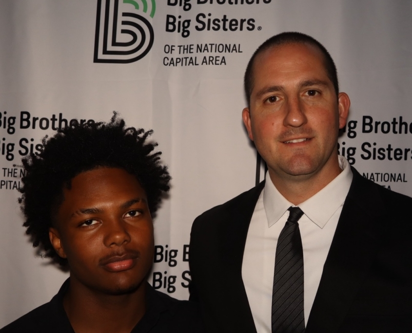 a teenage male and an adult male smiling for a photo together